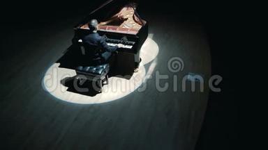舞台上的大<strong>钢琴</strong>：一个穿着黑色西装的优雅男子在音乐厅的舞台上演奏大<strong>钢琴</strong>